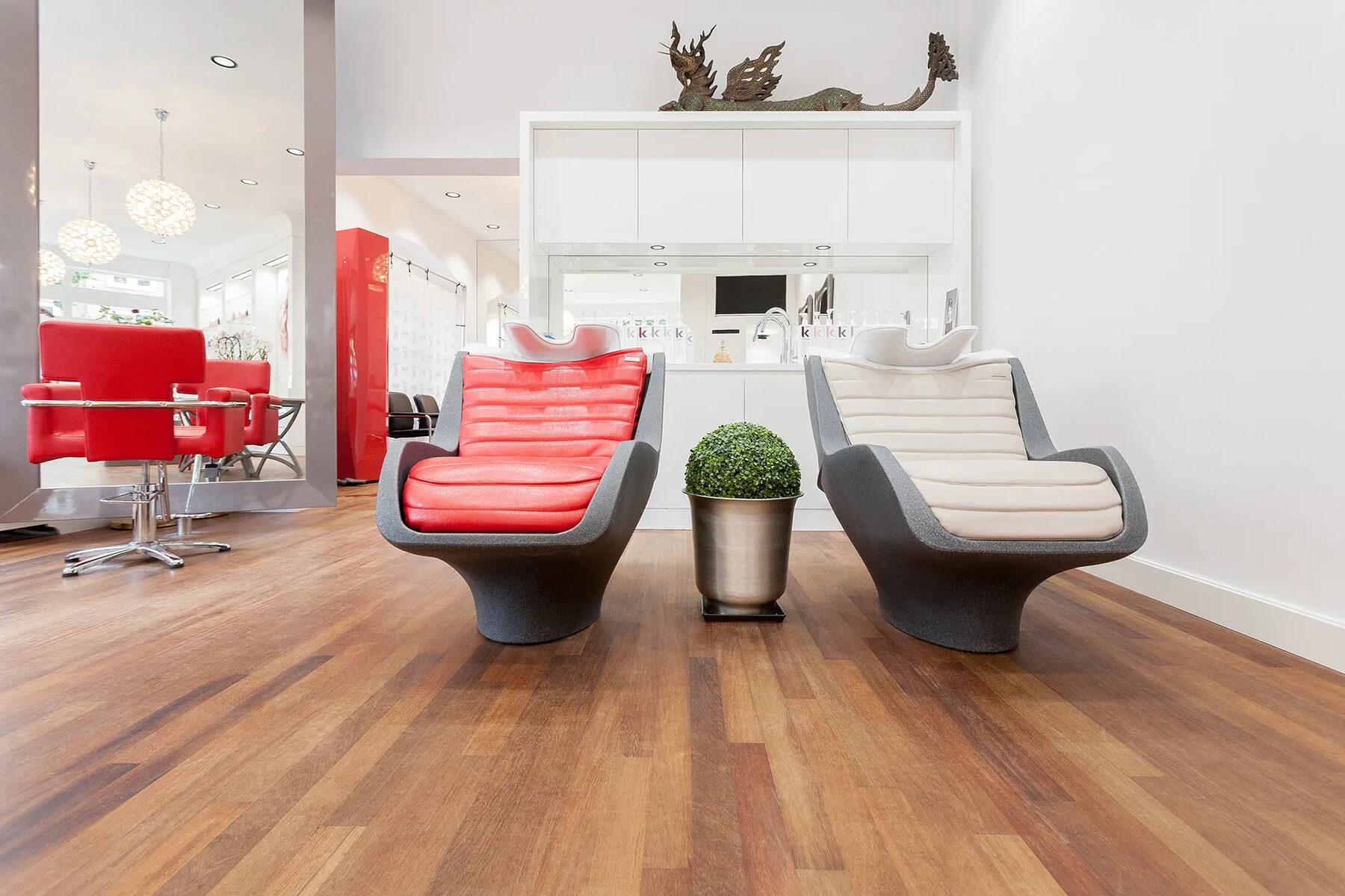 De salon van Kbal Super Natural met rode kappersstoelen